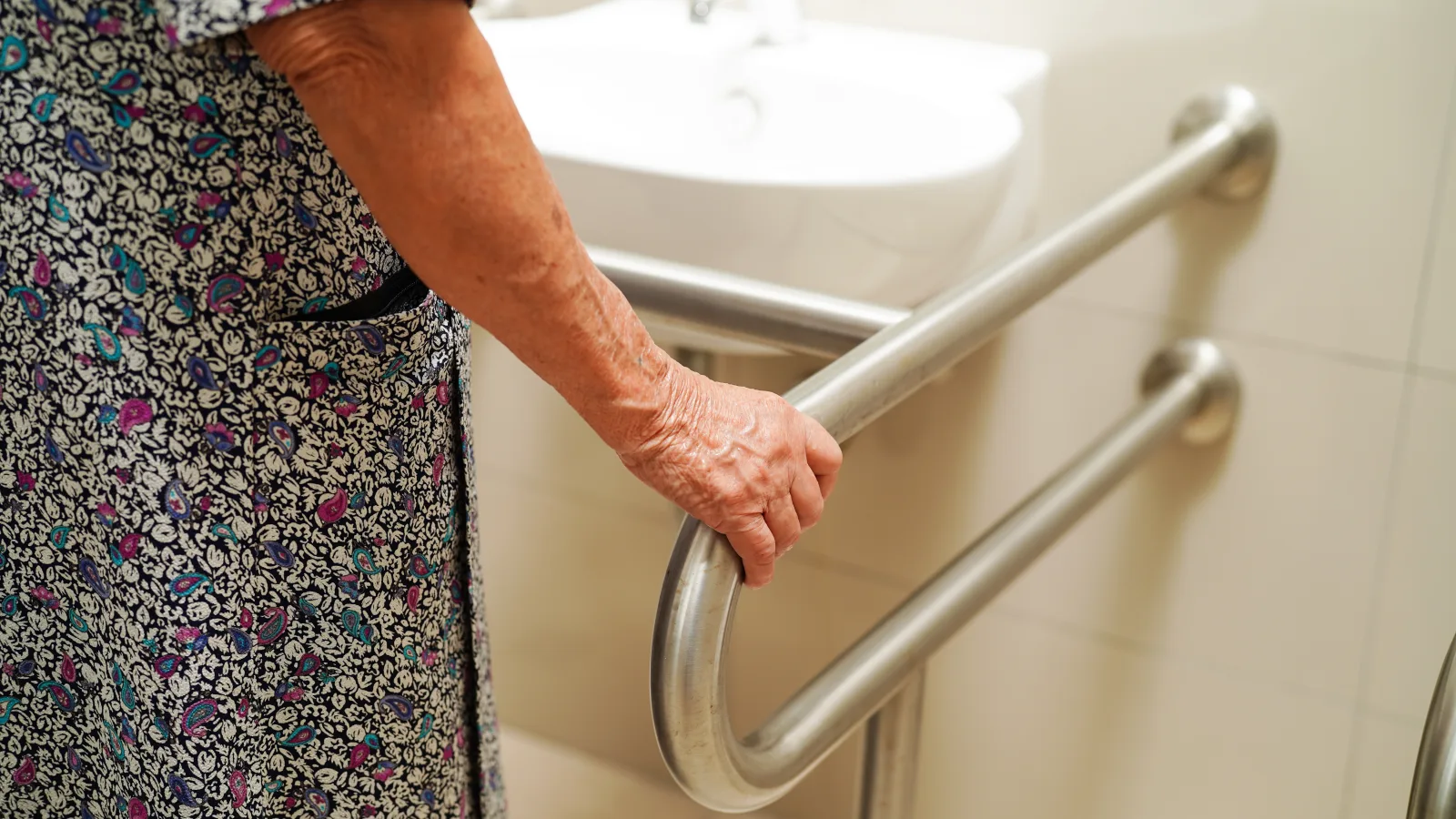 Personne senior utilisant une barre d’appui pour se déplacer en sécurité dans la salle de bain