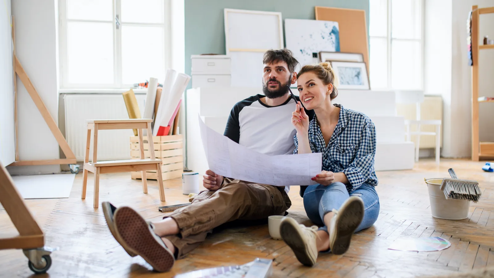 Couple examinant ensemble les plans d’une maison sur une table avant des travaux