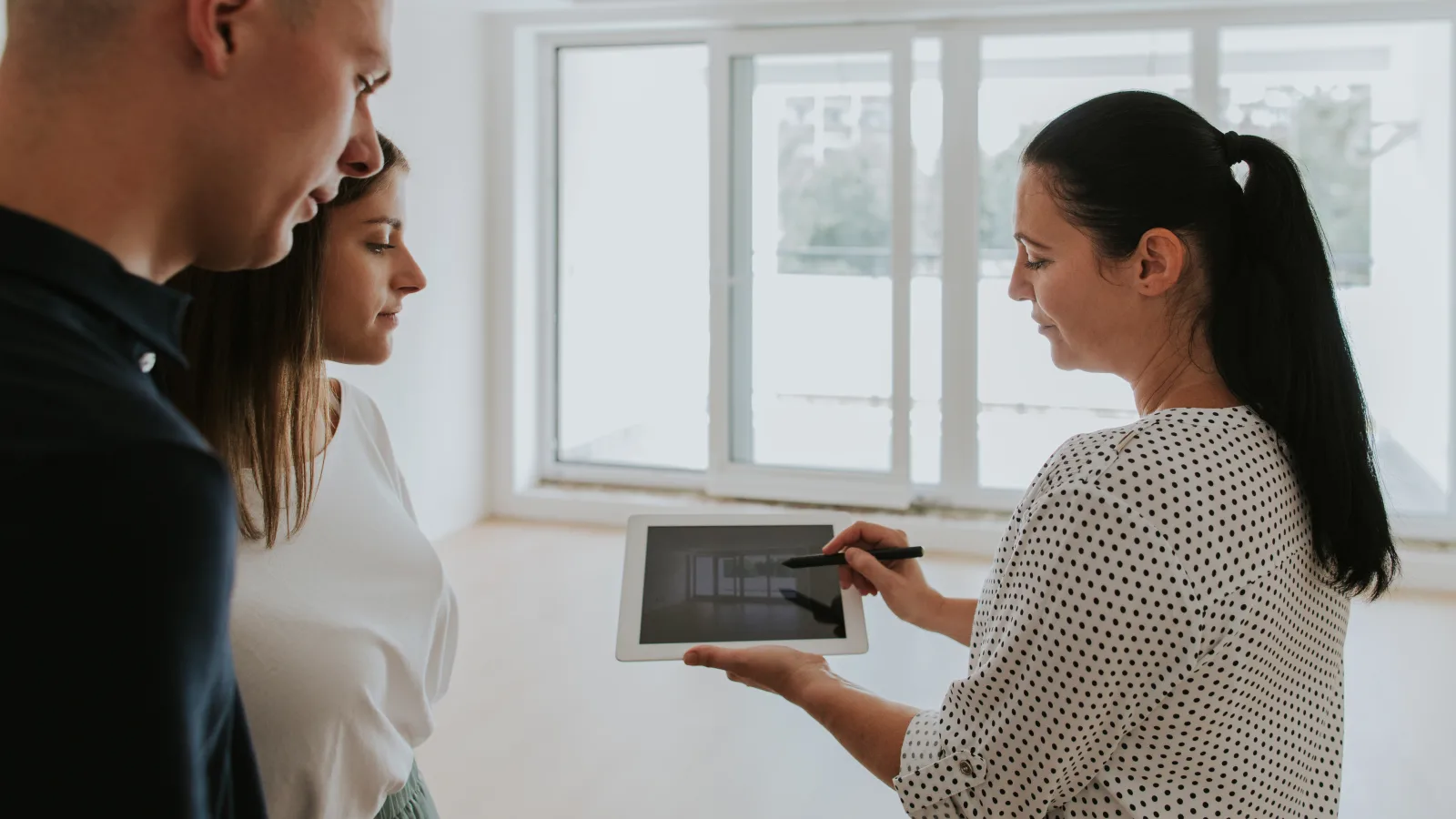 Conseillère présentant des plans de rénovation sur tablette à un couple attentif