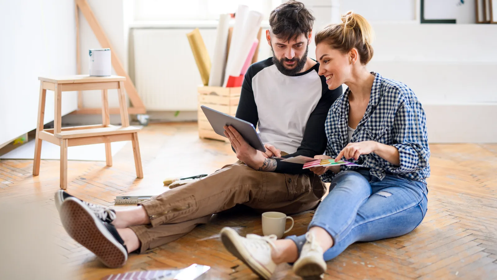 Couple préparant la rénovation de son logement à l’aide de plans et d’une tablette