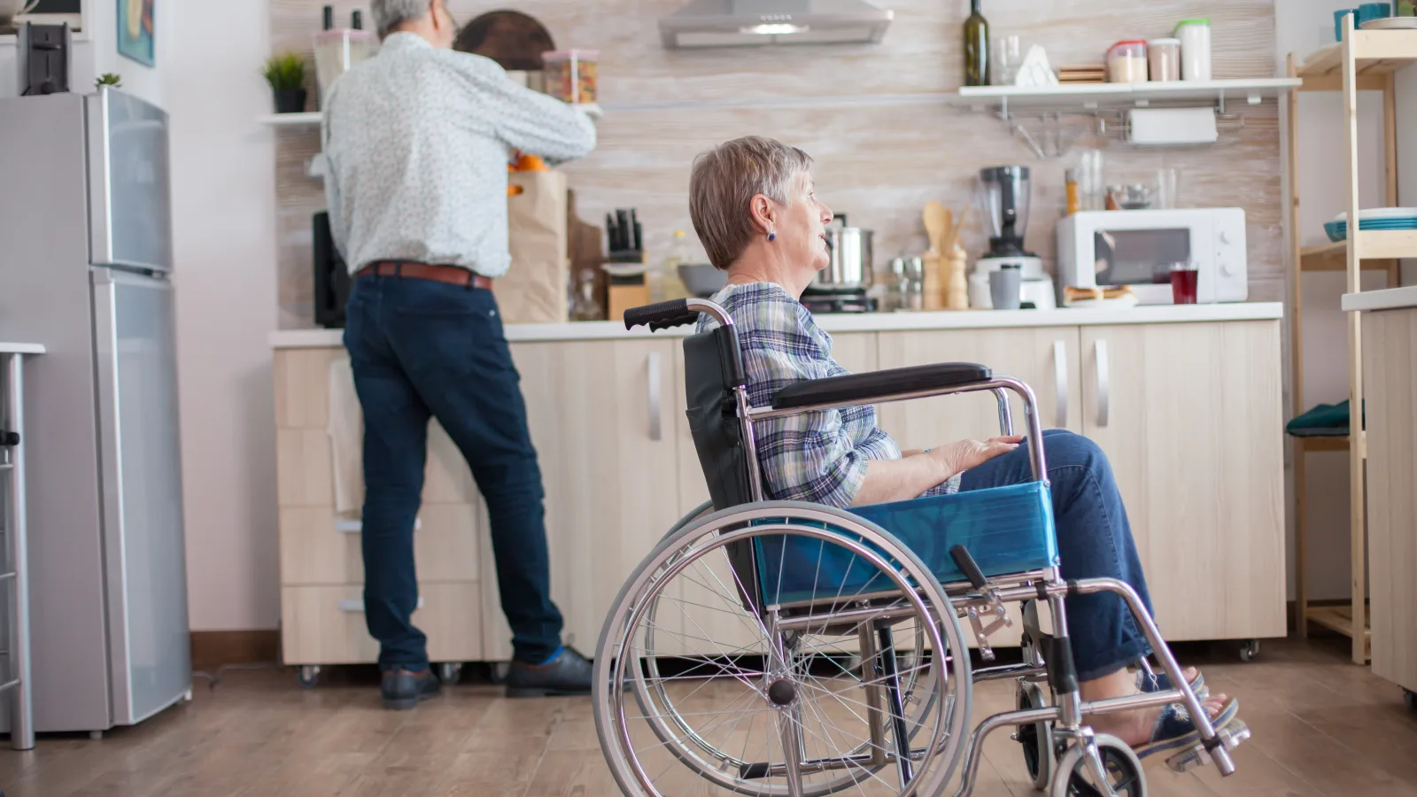 Couple senior dans une cuisine adaptée, avec l’un des occupants installé en fauteuil roulant