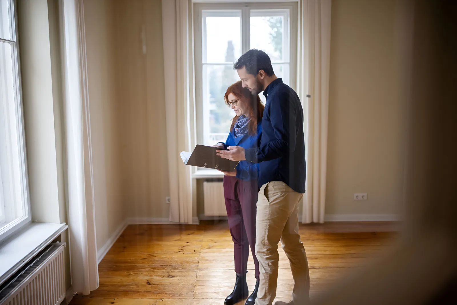 Un couple consulte des documents dans un appartement lumineux et encore vide avant son emménagement