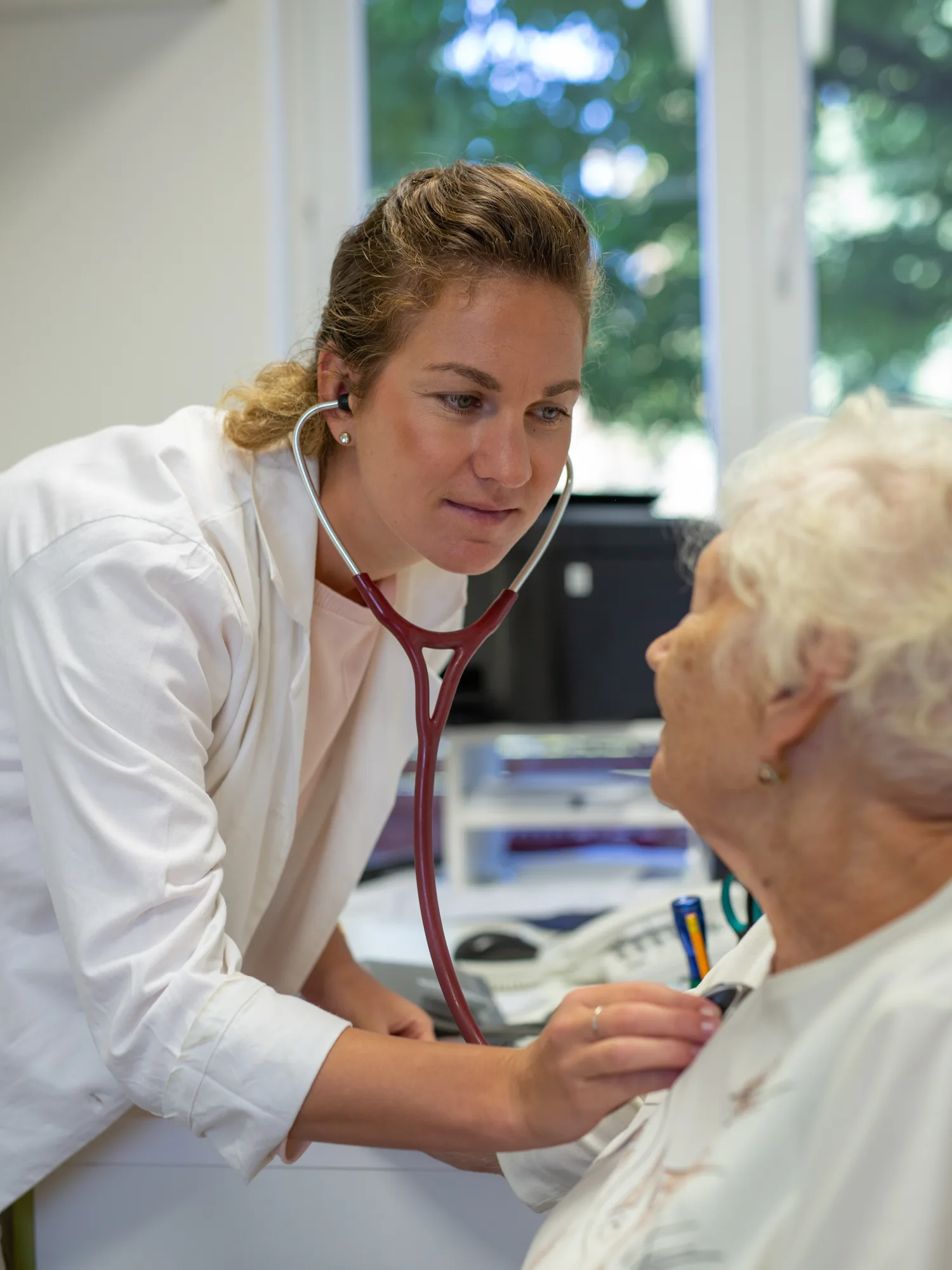 Une médecin ausculte une femme senior avec un stéthoscope au cours d’une consultation en cabinet