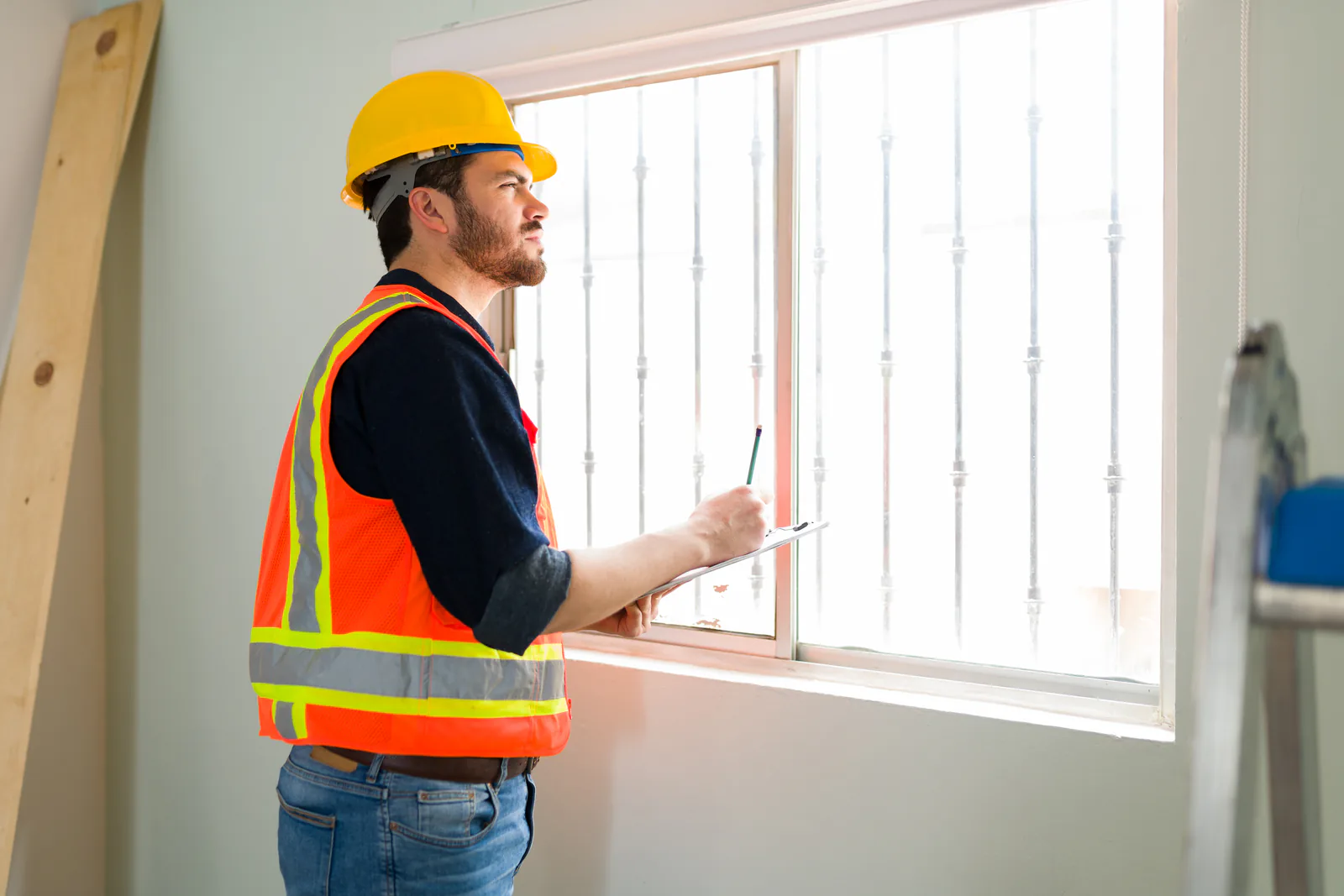 Un artisan contrôle une fenêtre et les parois d’un logement en cours de rénovation énergétique